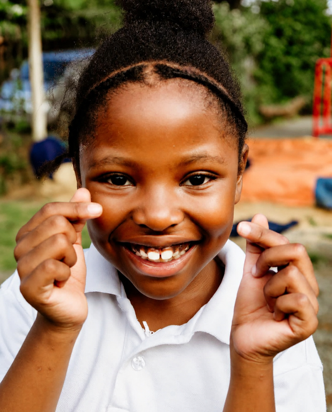 A smiling JENS learner in a white school shirt looking at the camera on the school playground