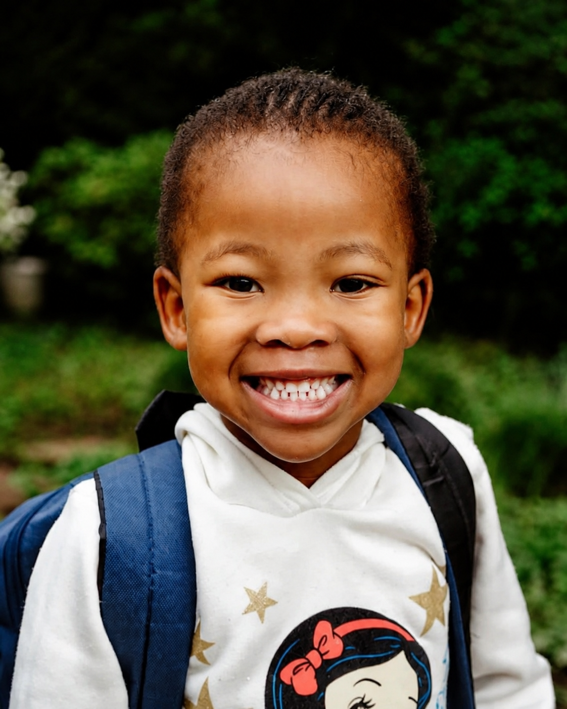 A smiling JENS learner wearing a blue school backpack