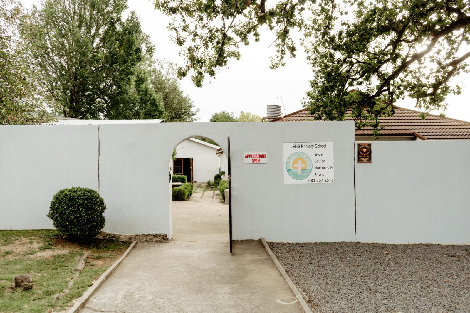 The entrance gate of JENS Primary School with the school sign beside it