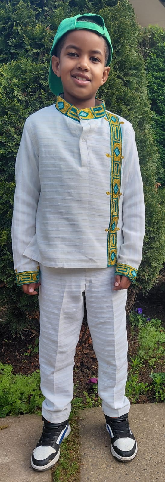 A JENS learner celebrating Heritage Day in traditional white clothing with green and gold detail
