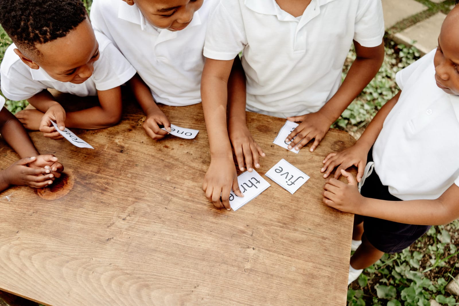 Learners working with number and word cards at a table outside