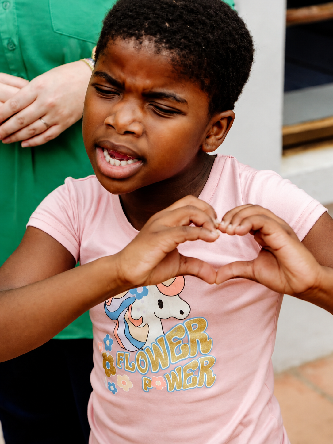A JENS learner making a heart shape with her hands and smiling