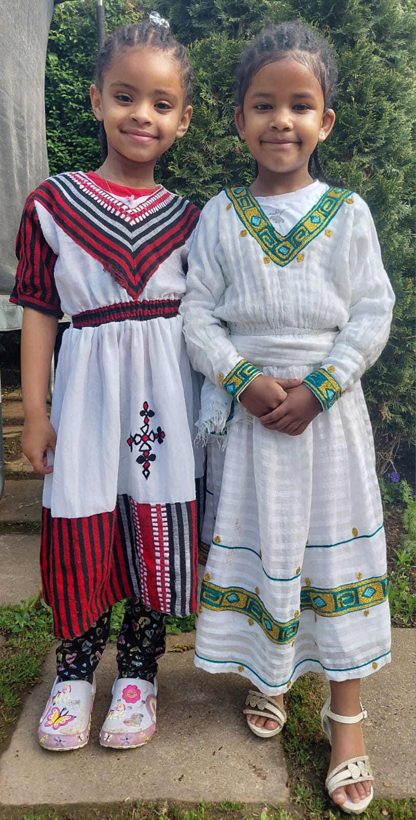 Two JENS learners celebrating Heritage Day together in traditional white dresses with colourful detail