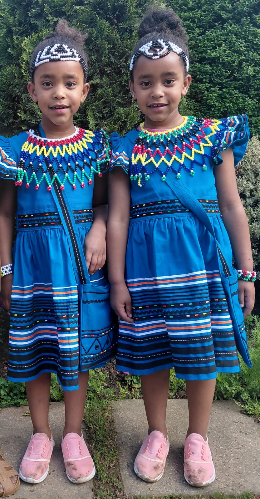 Two JENS learners celebrating Heritage Day together in matching blue traditional dresses and beadwork