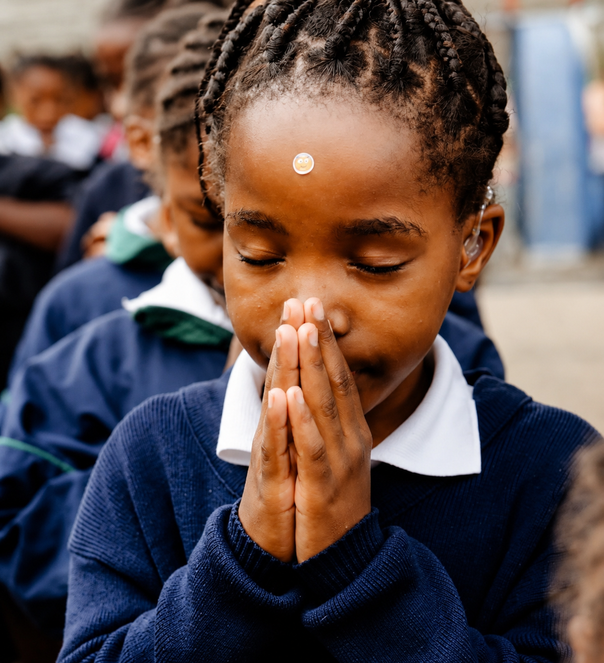A JENS learner with her hands together in prayer during a quiet moment at school
