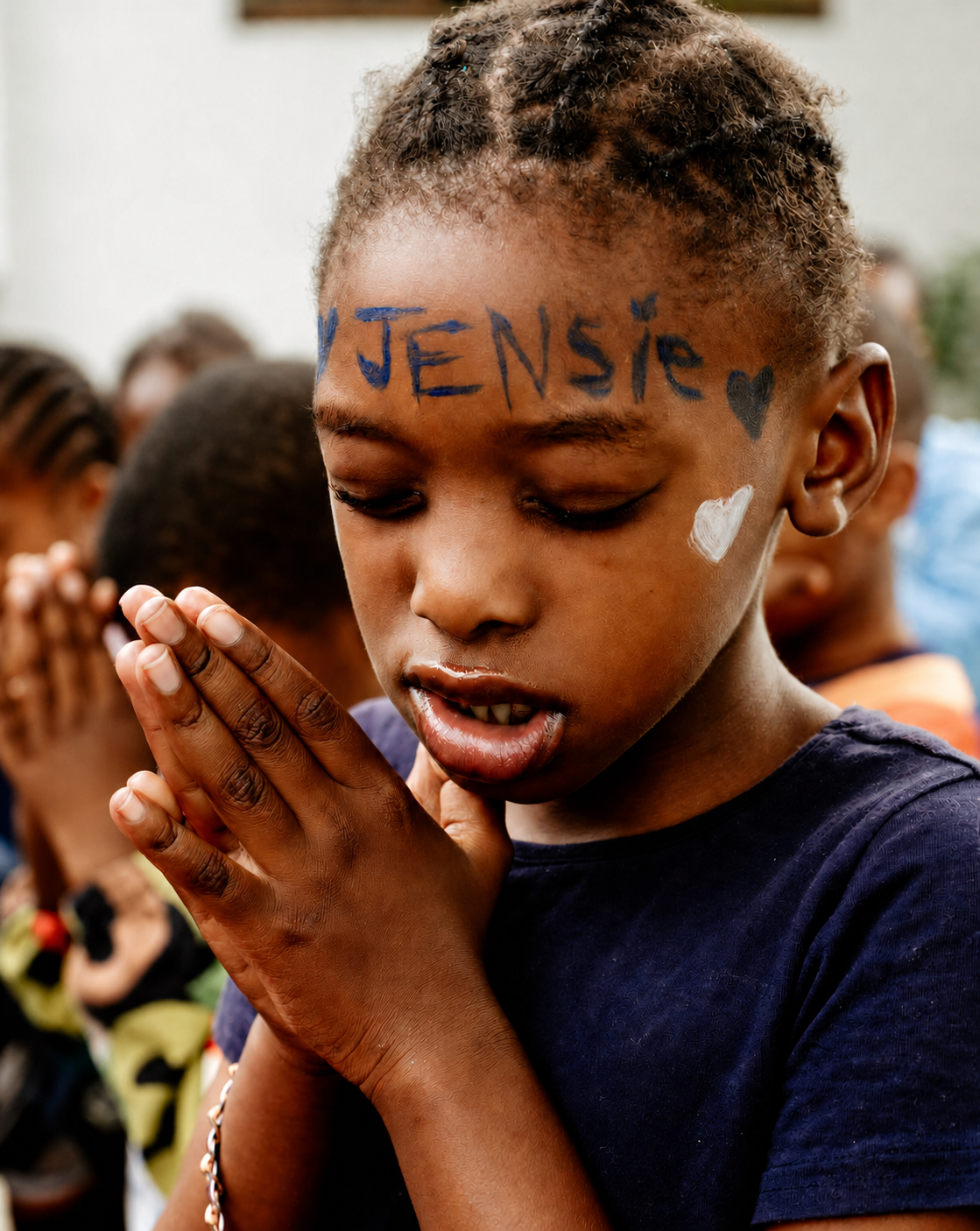 A JENS learner with “JENSie” and a heart painted on her face, hands together in prayer